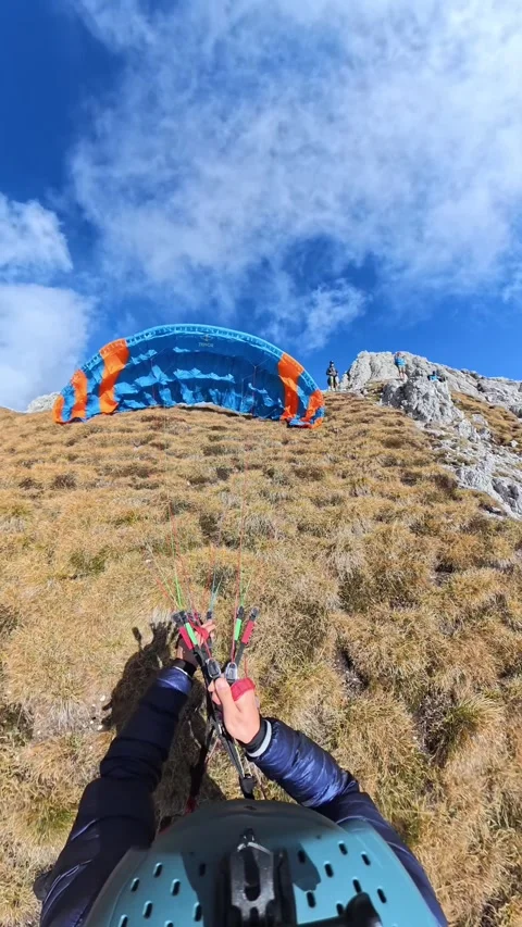 A Paraglider Gets Ready For Takeoff on a Grassy Mountain Slope Beneath a Bright Stock Footage 334406141