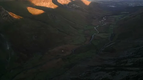A paraglider gliding down a dark mountain valley Vidéo 229412117