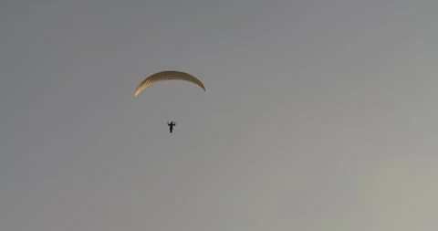 A paraglider gracefully soars through a beautiful, clear sky filled Stock Footage 285346204