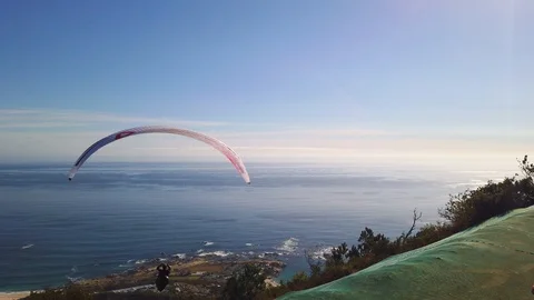 Paraglider heading out toward ocean from mountain in Cape Town Stockbeeldmateriaal 126983886