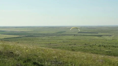The paraglider hovers over the fields Stock Footage 76736990