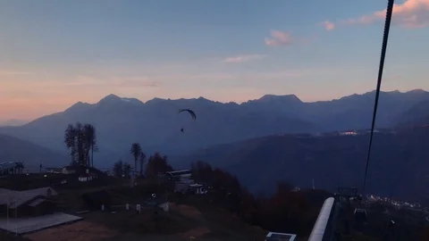 Paraglider with a passenger flies from the rocky mountains Stock Footage 106853653