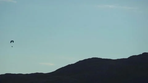 A paraglider passing behind a mountain Stock Footage 241534765