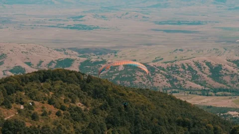 Paraglider peacefully gliding through the air with his glider wing above a Video stock 266258227