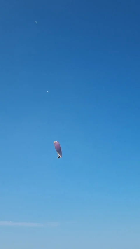 Paraglider performing acrobatic maneuvers in blue sky. Vertical video. Stock Footage 286007789