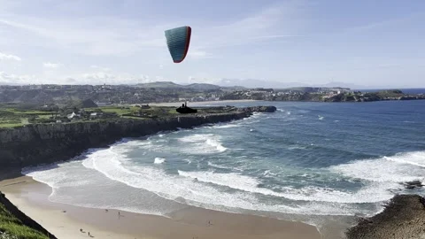 Paraglider Performs Acrobatics Over Beach and Ocean – Cliffside View in Video stock 304321658