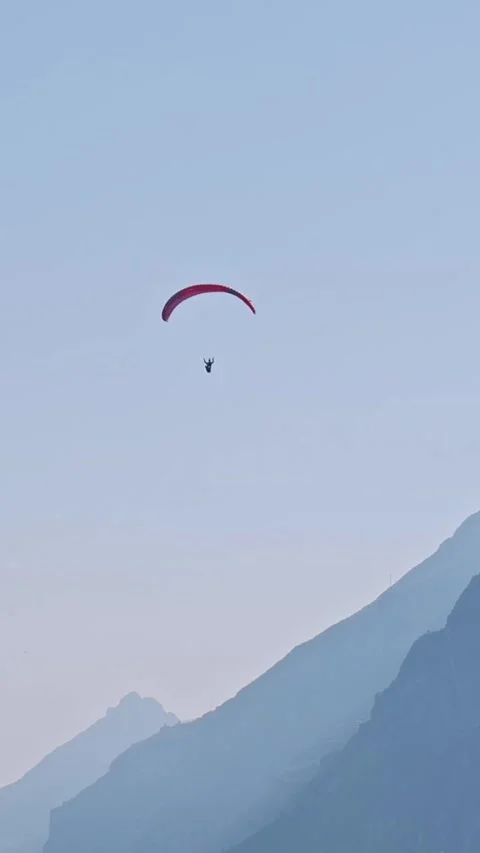 Paraglider pilot flying high over mountain blue haze VERTICAL shot Video stock 313601423