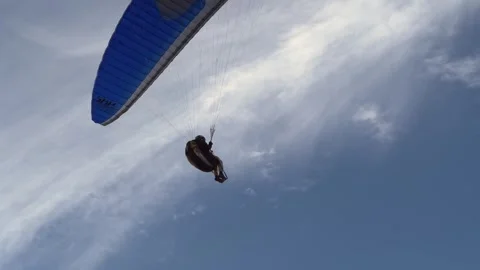 A paraglider pilot gracefully glides against the backdrop of the azure Stock Footage 274344343