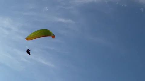 A paraglider pilot gracefully soars against the backdrop of the azure sky, Stock Footage 274329269