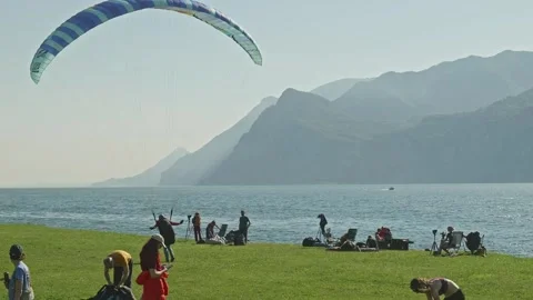 Paraglider pilot safe landing on grass field on Lake Garda shorline Vídeo Stock 313615577