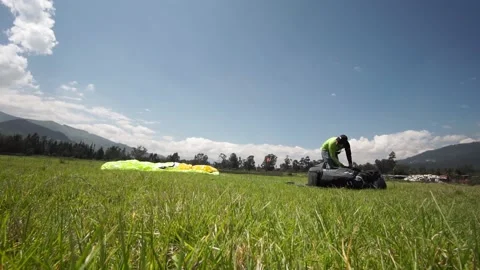 Paraglider preparing for saving the parachute after a paraglide in a green Stock-Footage 133748197