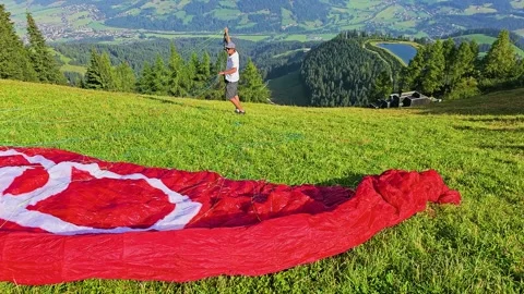 Paraglider preparing for takeoff above Kitzbuhel, Austria, with bright red Stock Footage 337190841