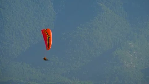 Paraglider with red canopy soaring high above the mountains Video stock 320891852