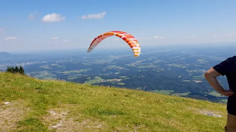Paraglider Soaring Above Forest Under Blue Sky and White Clouds Over Mountains Vídeo Stock 331853656