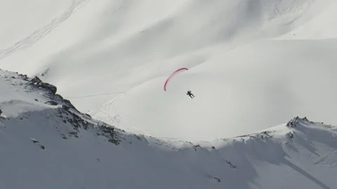 Paraglider soaring above pristine, snowy, rugged mountain peaks which Stock Footage 291957137