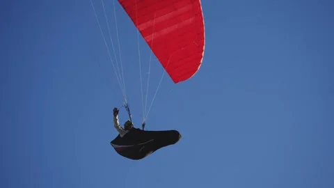 Paraglider soaring in clear blue sky with bright red canopy Stock Footage 311805184