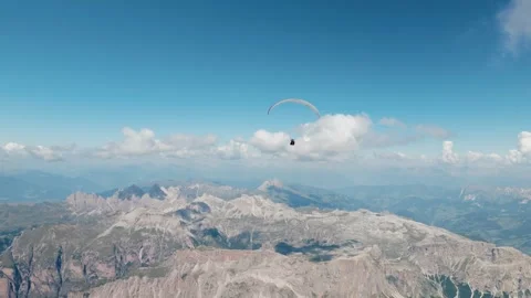 Paraglider Soaring High In A Clear Blue Sky Over Rocky Mountain Range In Vídeo Stock 345165605