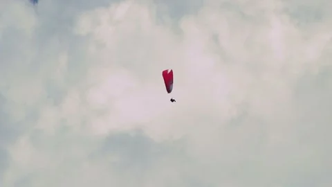 Paraglider soaring high in the deep blue sky above majestic white clouds. Video stock 347660438