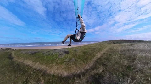 Paraglider soaring low over coastal dunes in Netherlands 動画素材 340215344