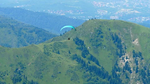Paraglider soaring over green mountain ridges on sunny day Stock Footage 340036965