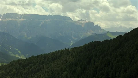 A paraglider soars above dense forested hills with a stunning backdrop of Video stock 283545933