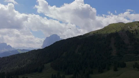 A paraglider soars above a forested mountain ridge with a stunning Stock Footage 283545852