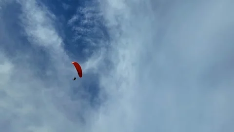 A paraglider soars against a backdrop of blue sky and white clouds. Stock Footage 305052133