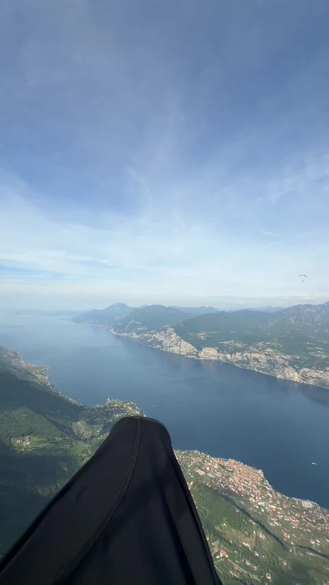 A Paraglider Soars High Above a Mountainous Landscape Under a Clear Blue Sky Vidéo 337142044