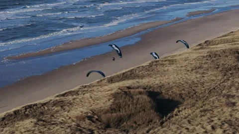 Paraglider soars rising and swooping in sky above windy Castricum beach, Stock Footage 264458658