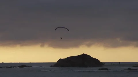 A paraglider soars through the sky at sunset over the Pacific Ocean near Stock Footage 284822975