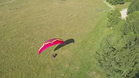 Paraglider takes flight. Man with red parachute runs down slop and begins Video stock 261502910