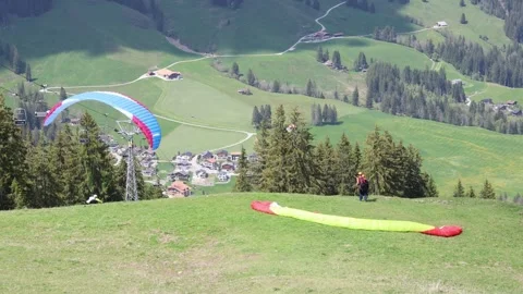 Paraglider taking of from the mountain while tandem jumpers prepare Video stock 274975001
