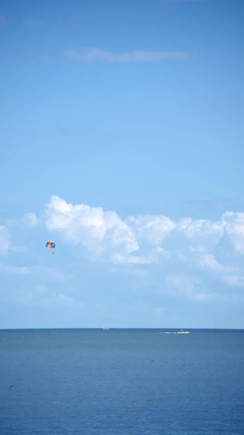 Paraglider trailing under blue sky and white clouds Stock Footage 343794435