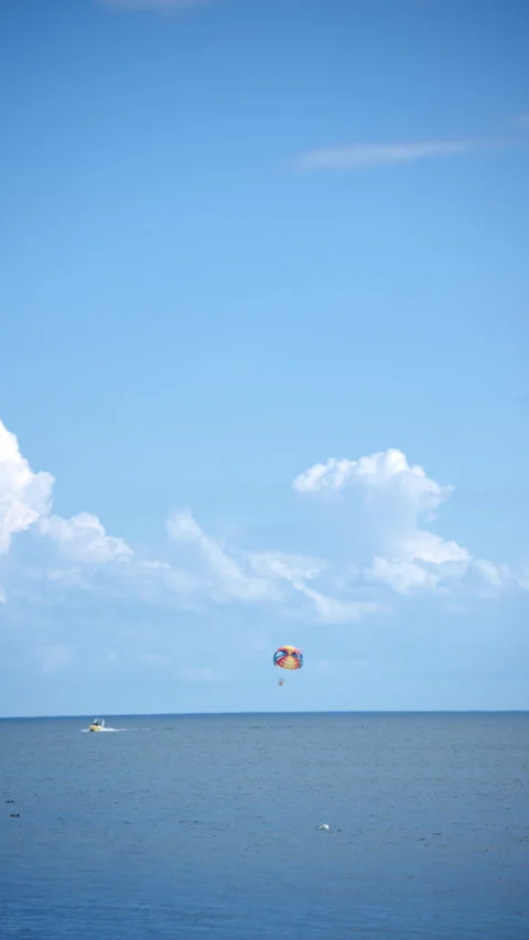 Paraglider trailing under blue sky and white clouds Stock Footage 343794437