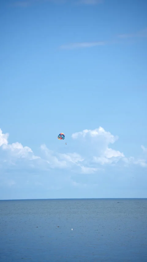 Paraglider trailing under blue sky and white clouds Stock Footage 343794440
