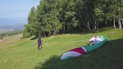 Paraglider untangles cord and wind catches parachute lifting it into the Video stock 253617207