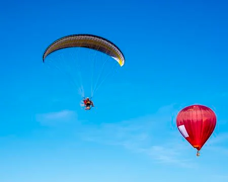 Paraglider withe red hot air balloon Stock Photos