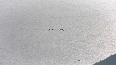 Paragliders drift across sunset sky above sea and islands near Fethiye Mugla Stock Footage 333875053