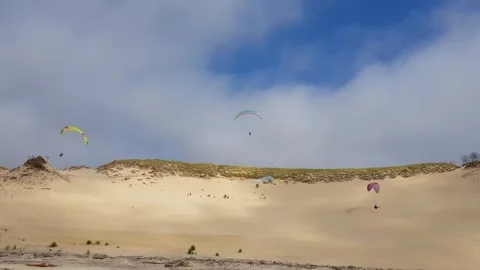 Paragliders fly over a sand dune Stock Footage 303733477
