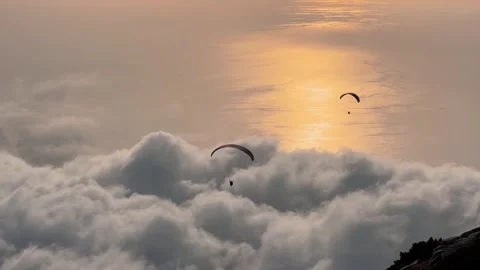 Paragliders flying above clouds over sea at sunset in Oludeniz 库存影片 346540608