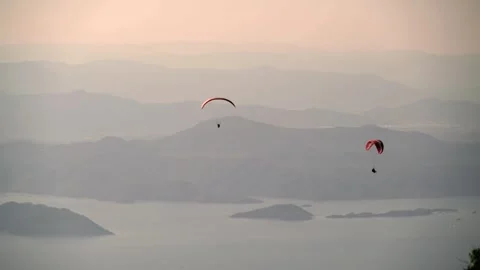 Paragliders glide above forested mountains and sea near Fethiye - Glider Sport Stock Footage 339934257