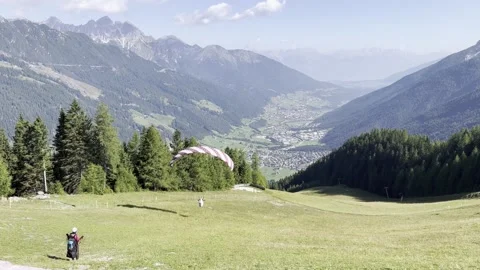 Paragliders launch from an alpine meadow below Elfer mountain in the Stubai Video stock 319053353