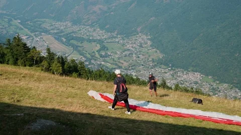 Paragliders preparing for launch on a hillside overlooking Luchon, France Stock Footage 292591250
