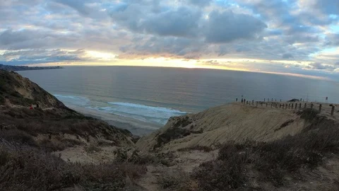Paragliders sails past cliffs over ocean under a cloudy sky Stock Footage 82104214