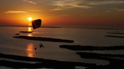 Paragliders in silhouette of setting sun reflected in the wate Stock Footage 65445686