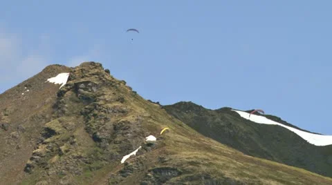 Paragliders Soaring Over Rocky Alaskan Mountain Ridge Stock Footage