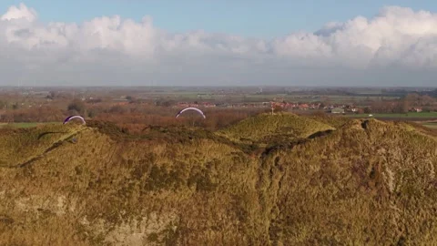 Paragliders soaring over sand dunes and countryside on a sunny day captured by Video stock 297050967