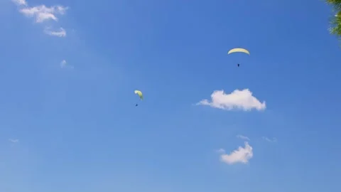 Paragliders soaring through blue sky with clouds in Turkey Stock Footage 332521825