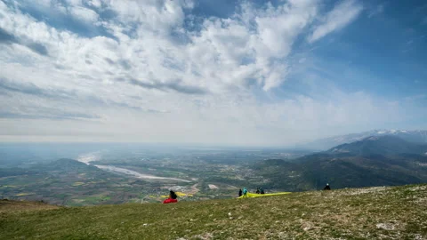 Paragliders take off from the mountain in turn. Timelapse. They spread their Stock Footage 143588024