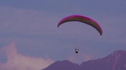 Paragliding amidst mountains in sky by humans enjoying the adventure in sky. Video stock 256142004